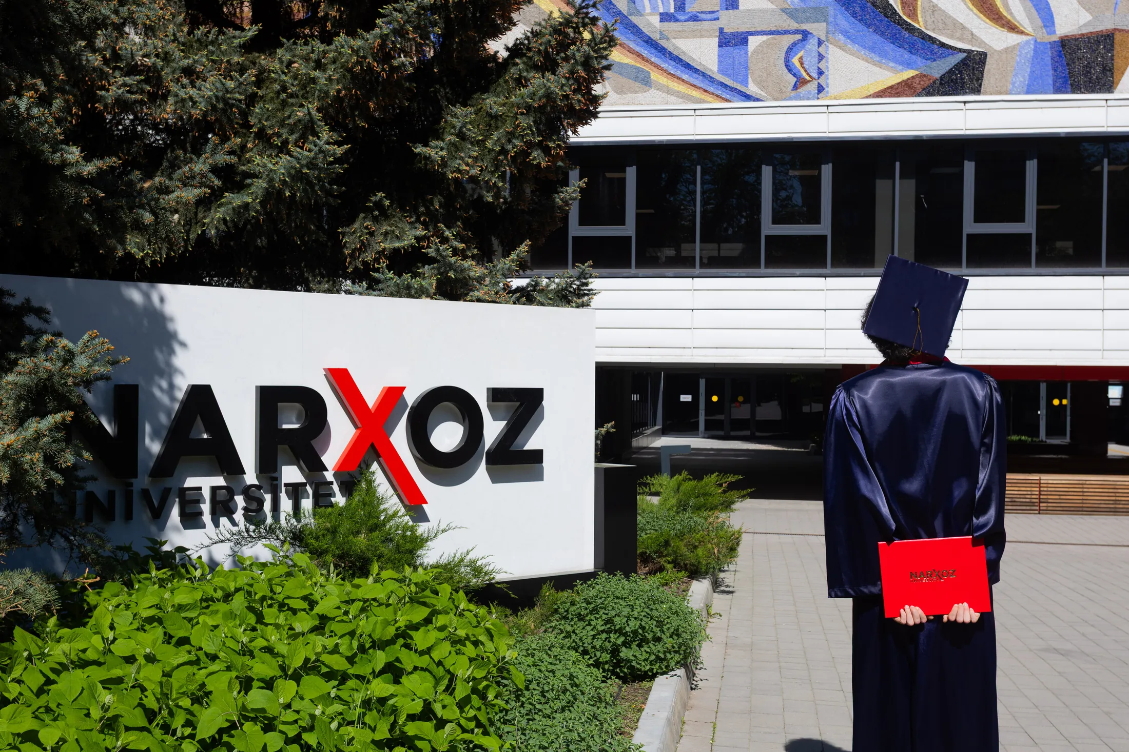 Выпускница у входа в Narxoz University